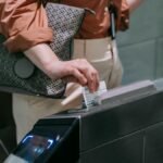 Close-up of woman using ticket at subway entrance turnstile, showcasing modern public transport system.