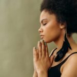 A young woman with afro hair practicing calming meditation indoors.