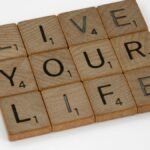 Scrabble tiles form the phrase 'Live Your Life' on a white background.