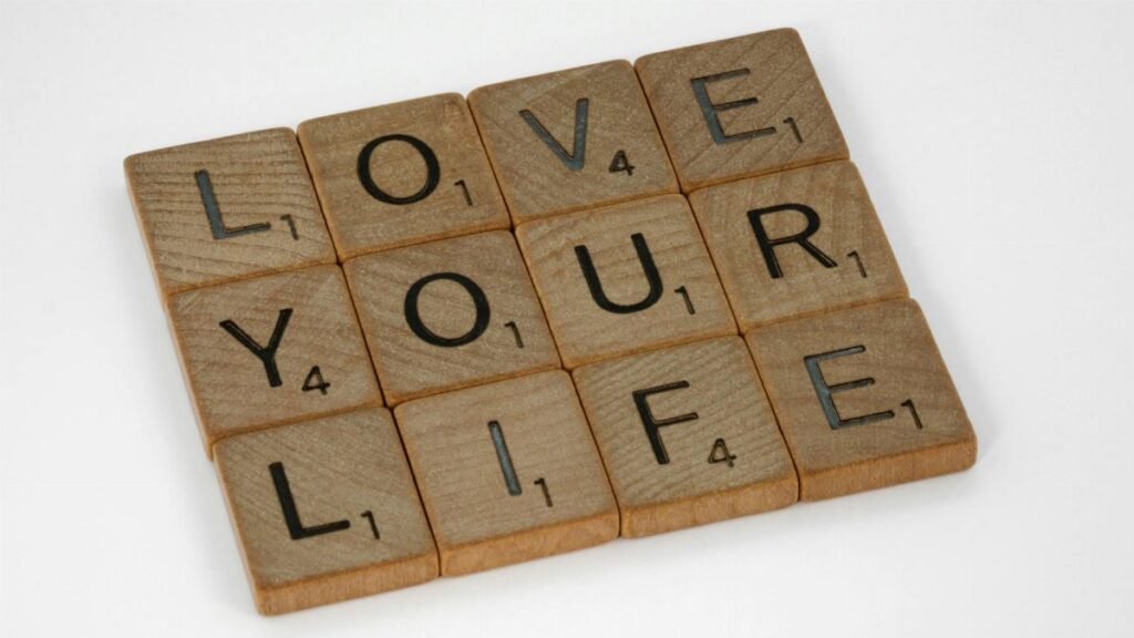 Scrabble tiles arranged to spell 'Love Your Life' against a white background, conveying a positive message.