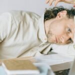 A tired Caucasian man at a desk, showing signs of exhaustion and stress, exemplifying workplace burnout.