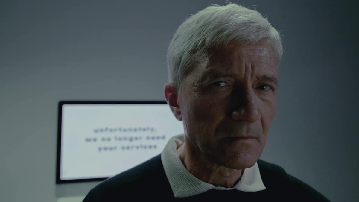 Elderly man looking thoughtful after reading a termination notification on screen.