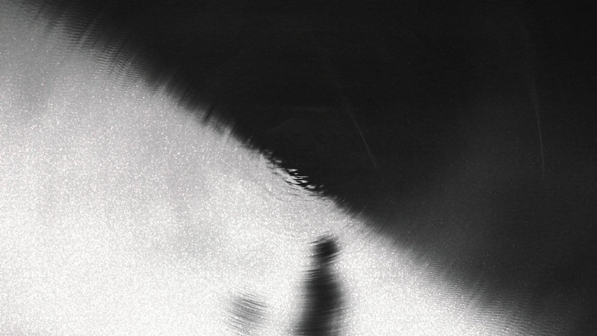 Blurred silhouette against a dramatic black and white gradient creating mystery.
