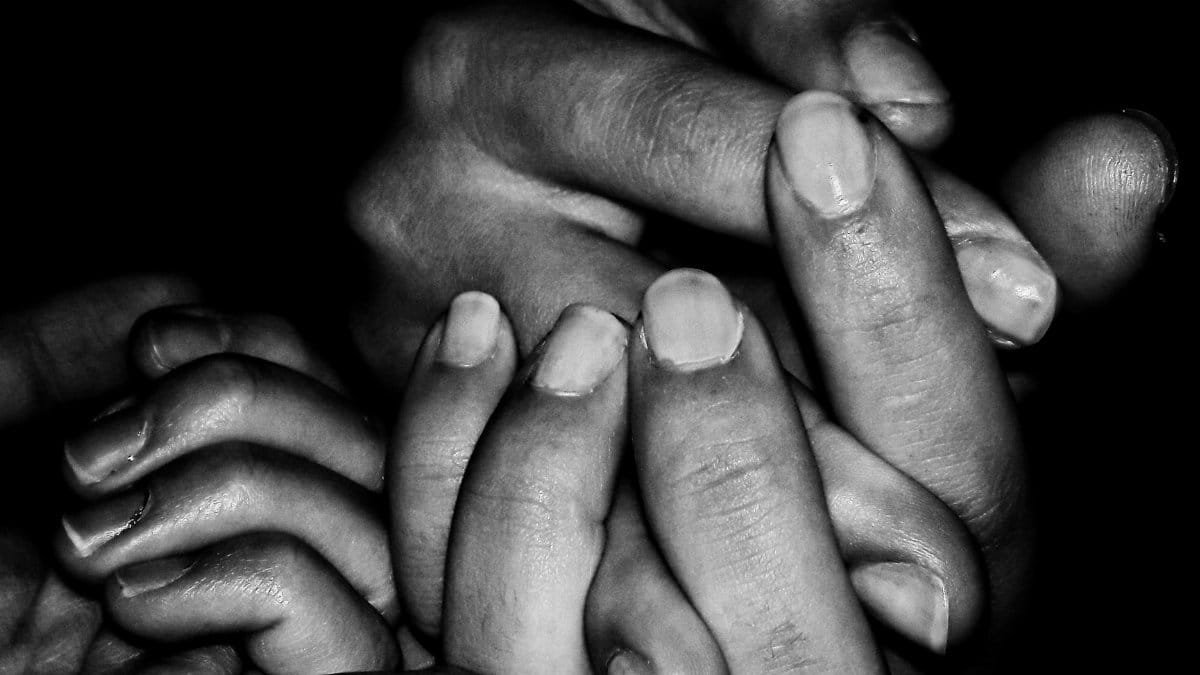 A black and white close-up of family hands holding each other, symbolizing unity and support.