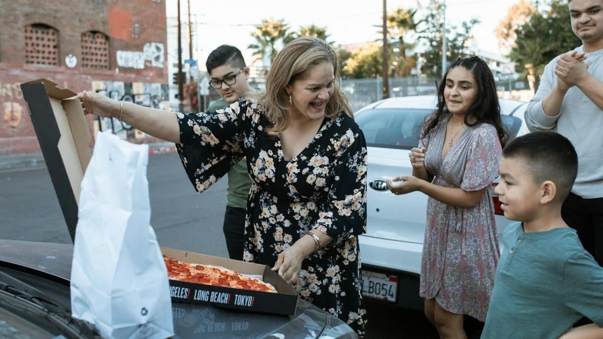 Happy family enjoying a pizza outing together in an urban setting.