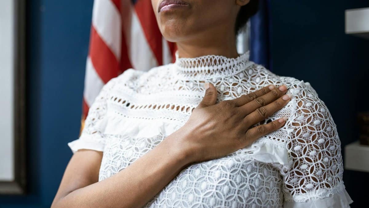 A confident woman in white lace dress pledges allegiance, symbolizing leadership and patriotism.