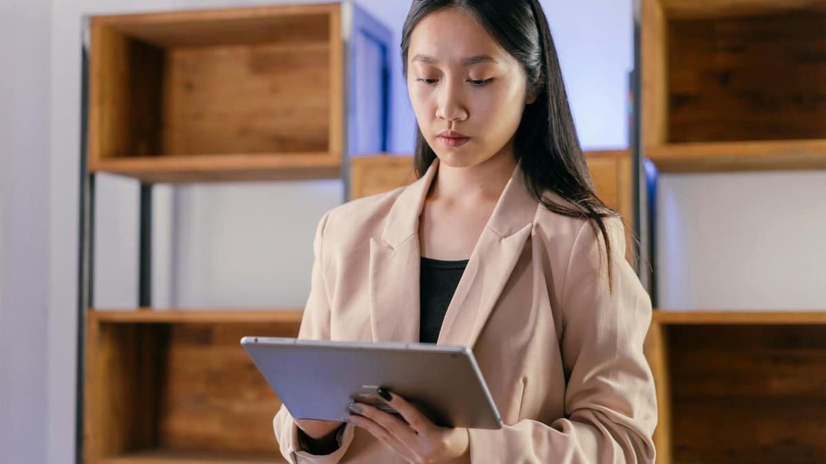 Young Asian businesswoman using a tablet in a modern office setting.
