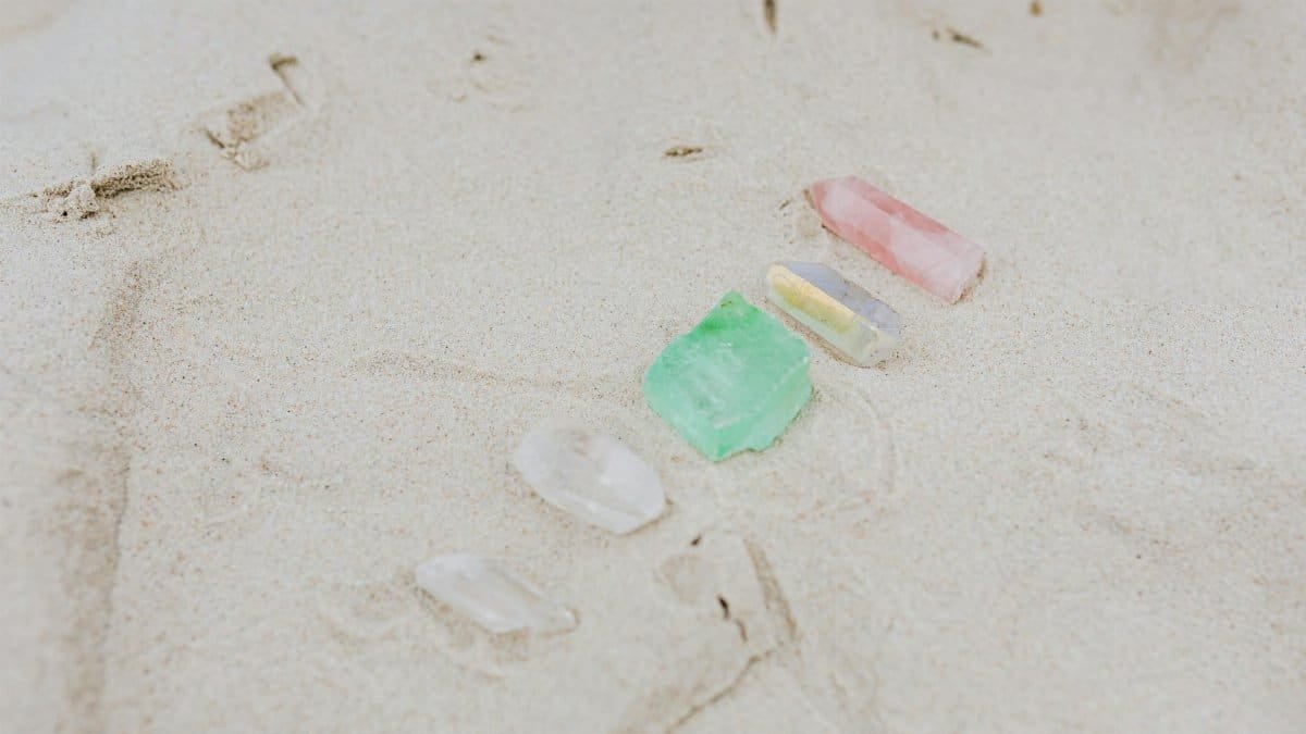 A serene arrangement of colorful crystals on sandy beach, showcasing tranquility and natural beauty.