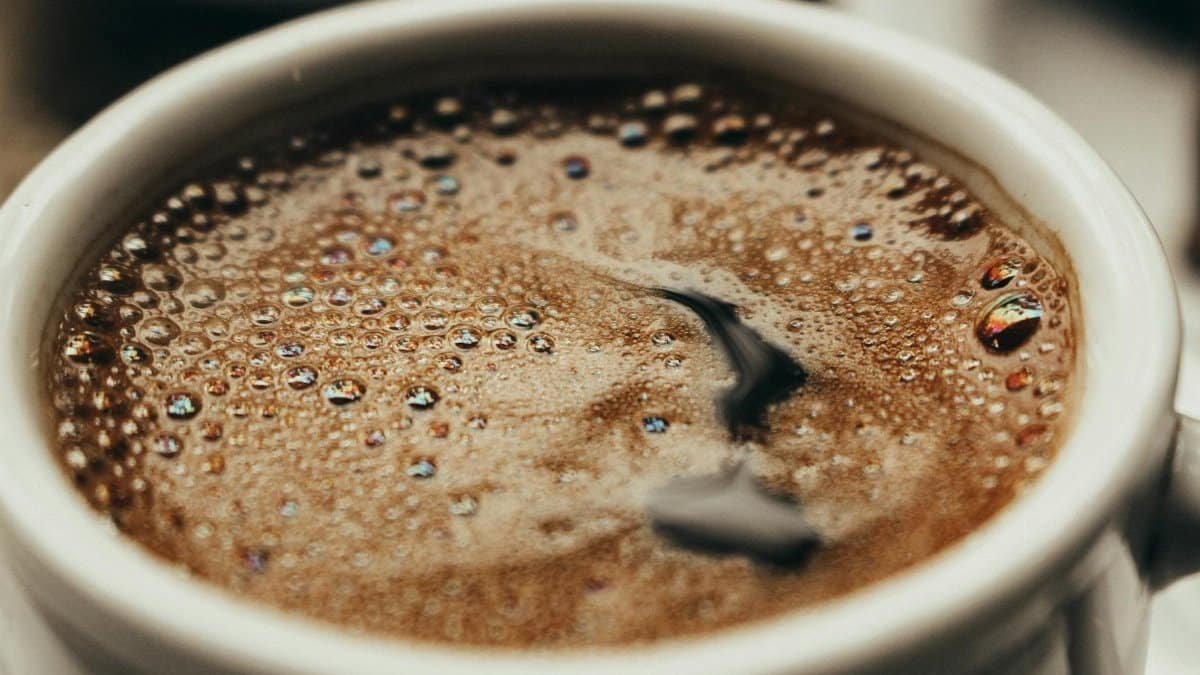 A close-up photo showcasing freshly brewed coffee in a white cup with visible bubbles.