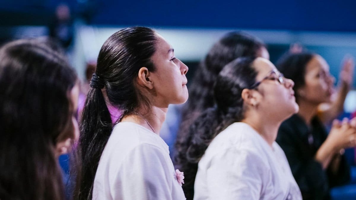 Individuals attentively engaged in a spiritual ceremony, capturing communal devotion indoors.