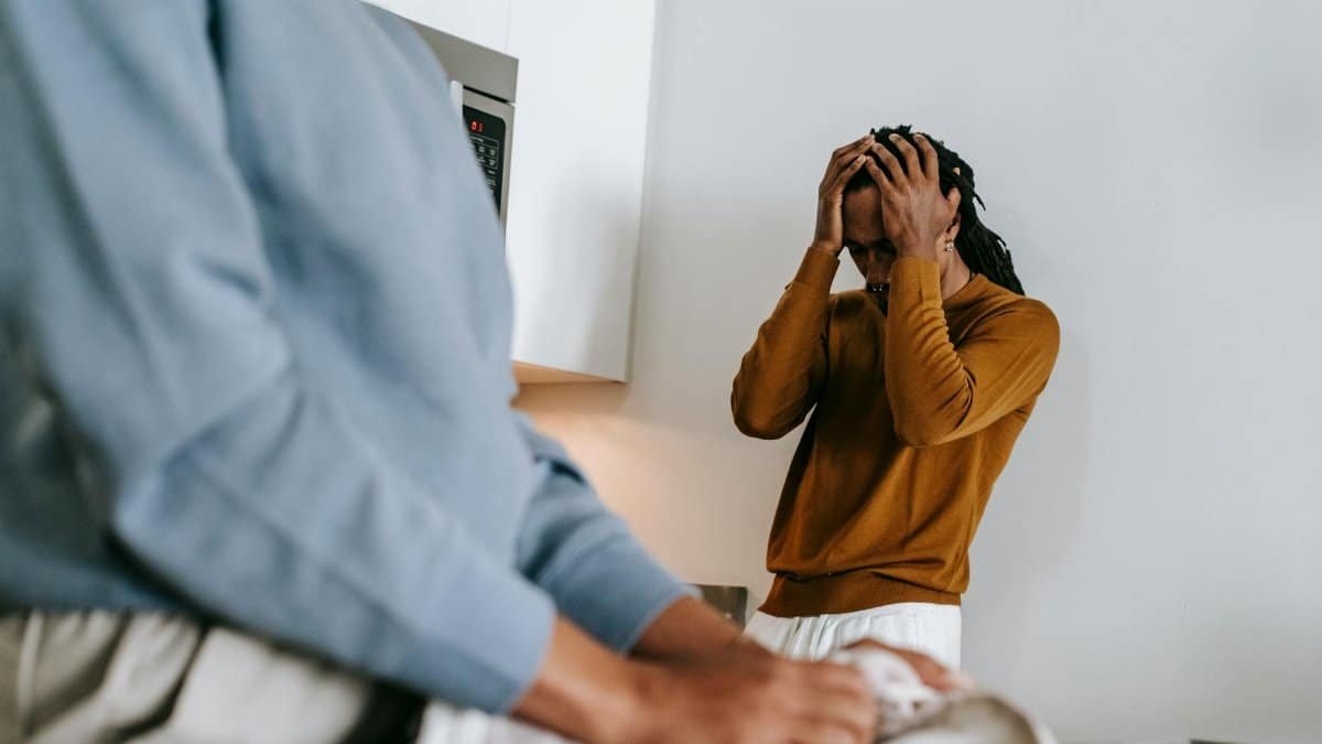 Young couple having a tense conversation in the kitchen, indoors.