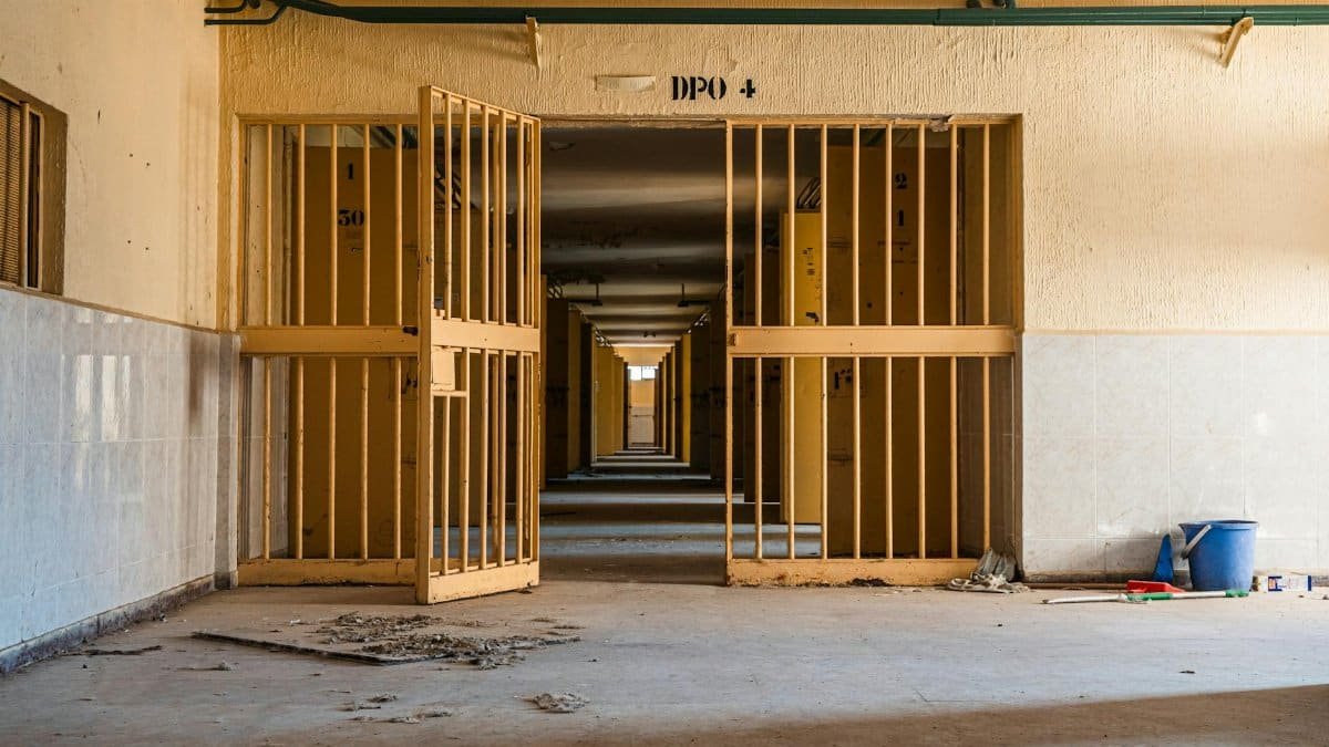 Interior view of an abandoned building featuring open gates and shown in a long corridor perspective.