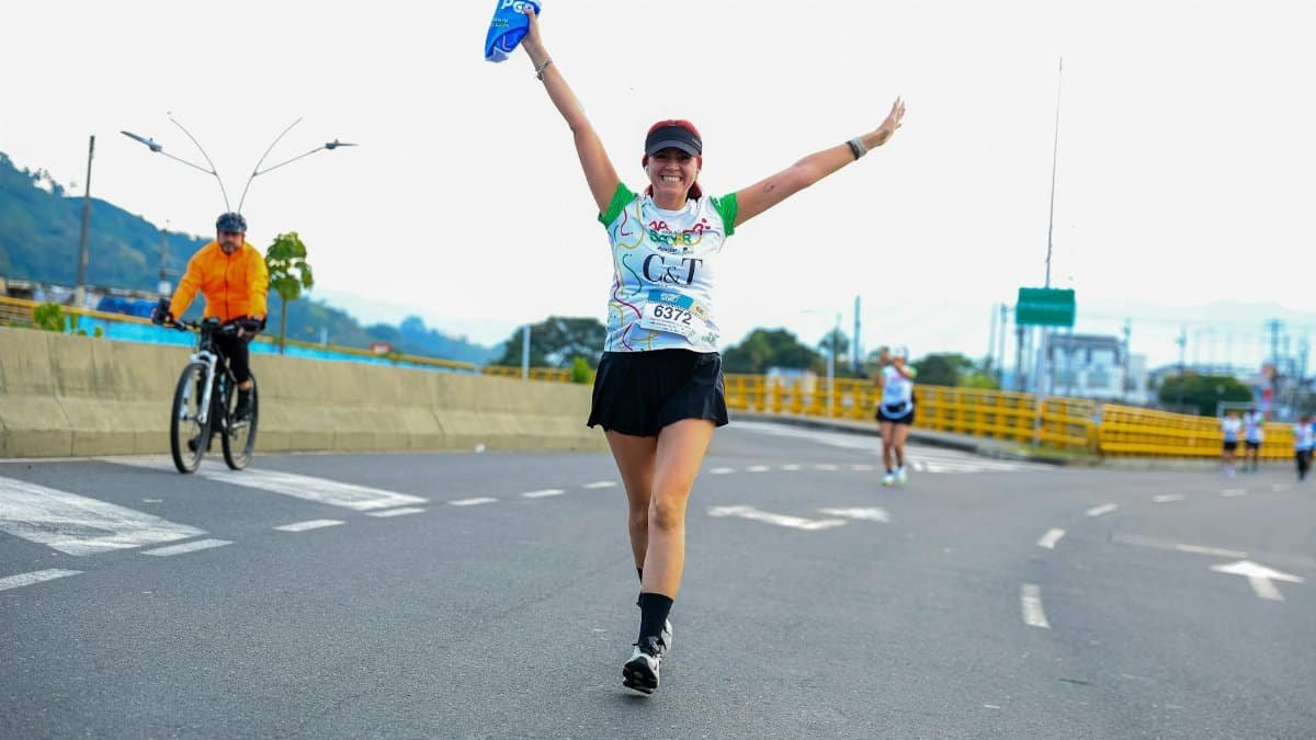 Happy female runner celebrates during a marathon outdoors on a road course.