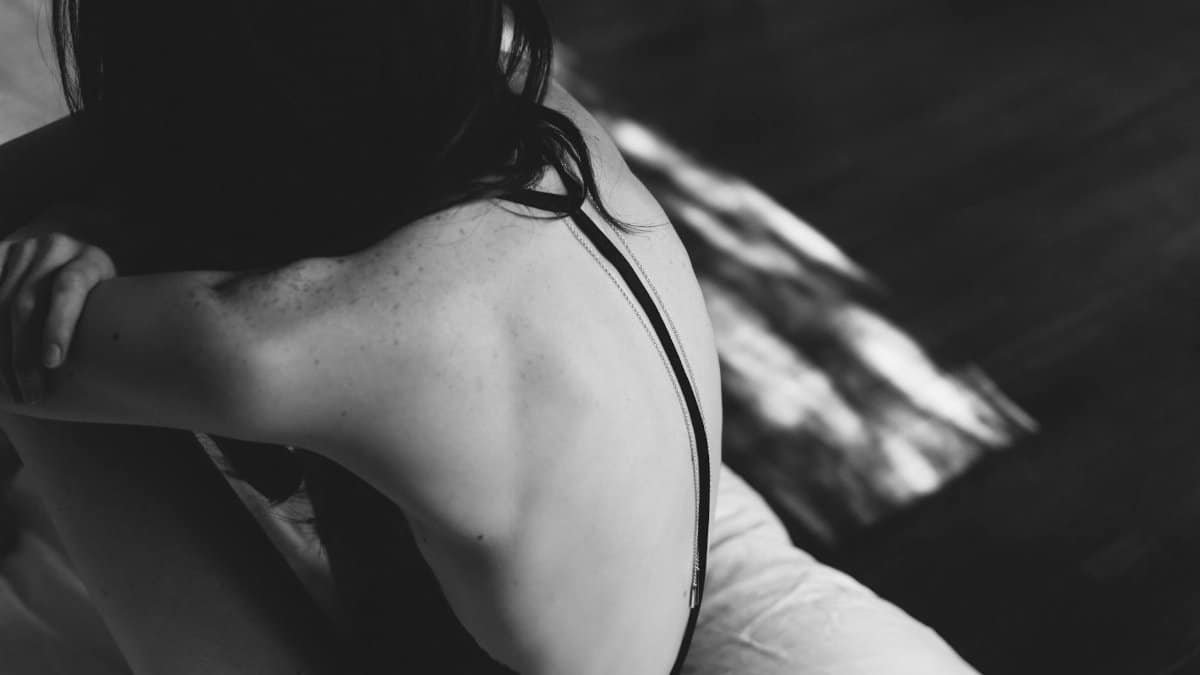 An artistic black and white portrait of a woman from behind, emphasizing form and texture.