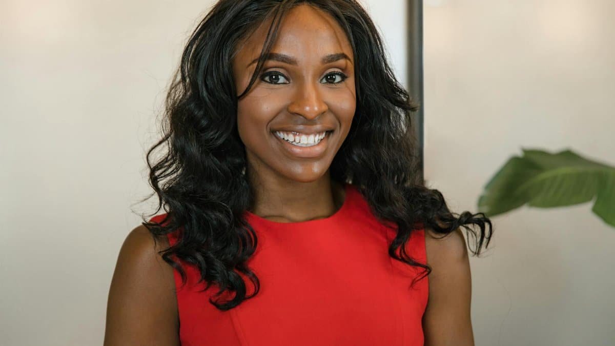 Confident businesswoman smiling in a vibrant red dress, exuding professionalism and positivity.