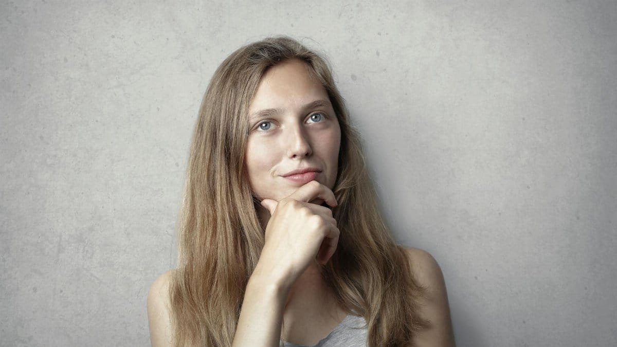 A thoughtful woman contemplates life in a simple portrait with a gray background.