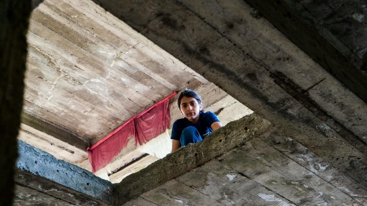 A young girl peers down from a concrete building in Tbilisi, Georgia.