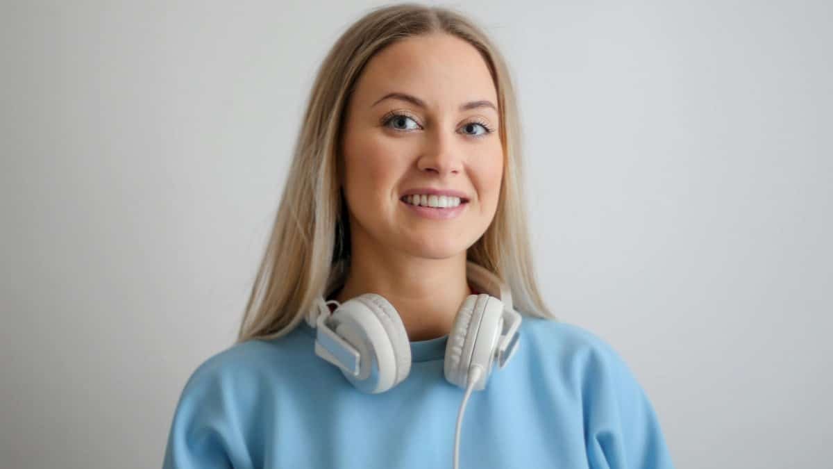 Portrait of a happy woman with headphones, wearing a blue top, smiling warmly.