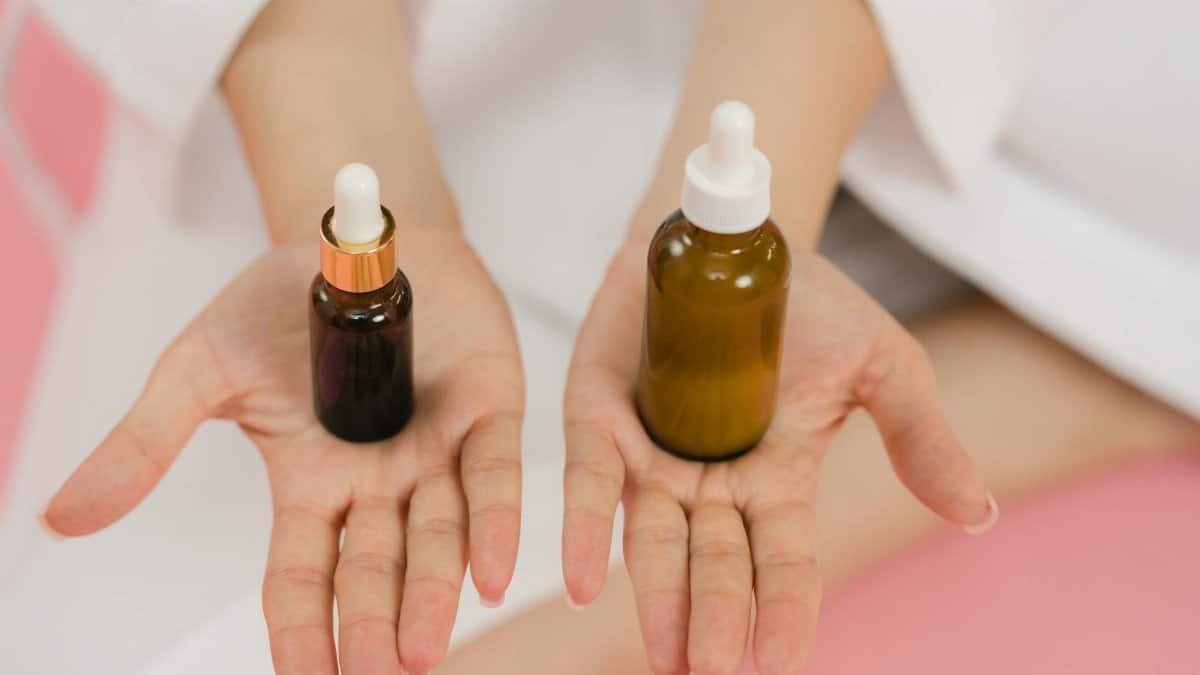Close-up of hands holding two cosmetic dropper bottles for skincare routine.