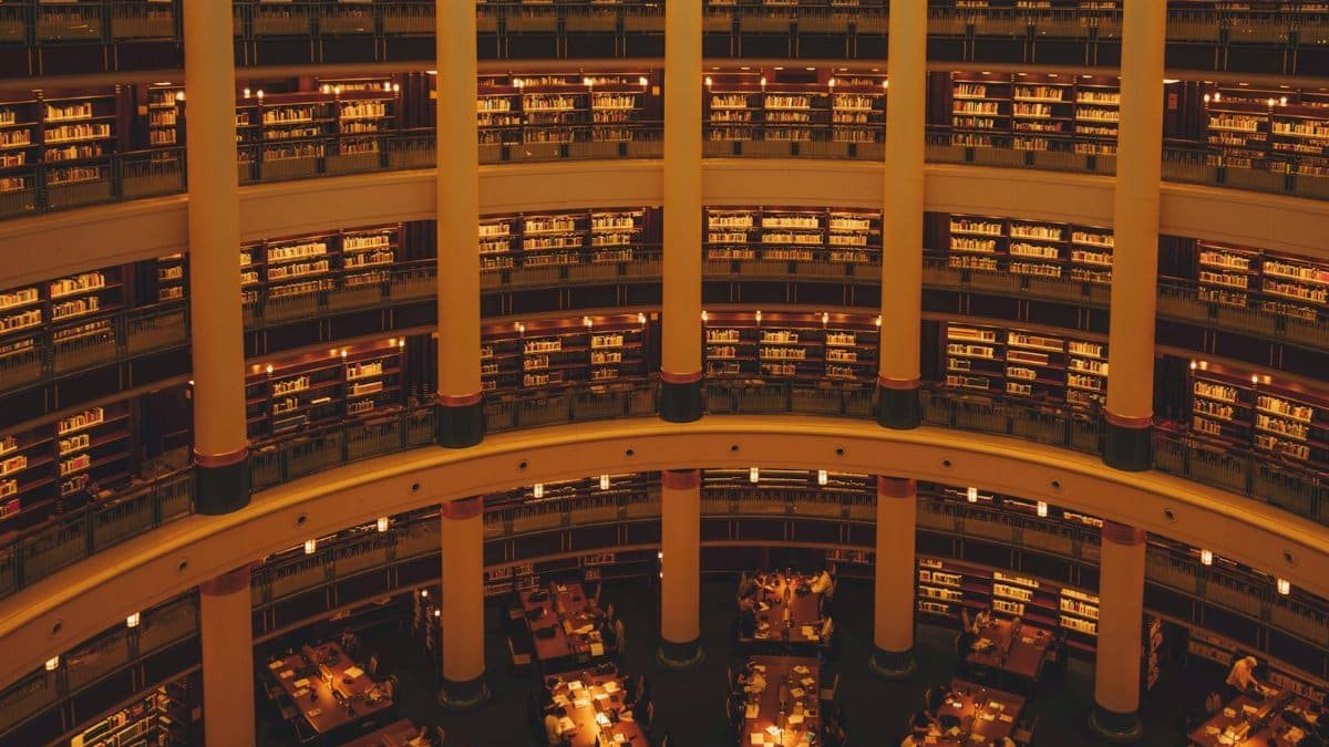 Majestic library with multiple levels and warm ambient lighting, showcasing architectural elegance.