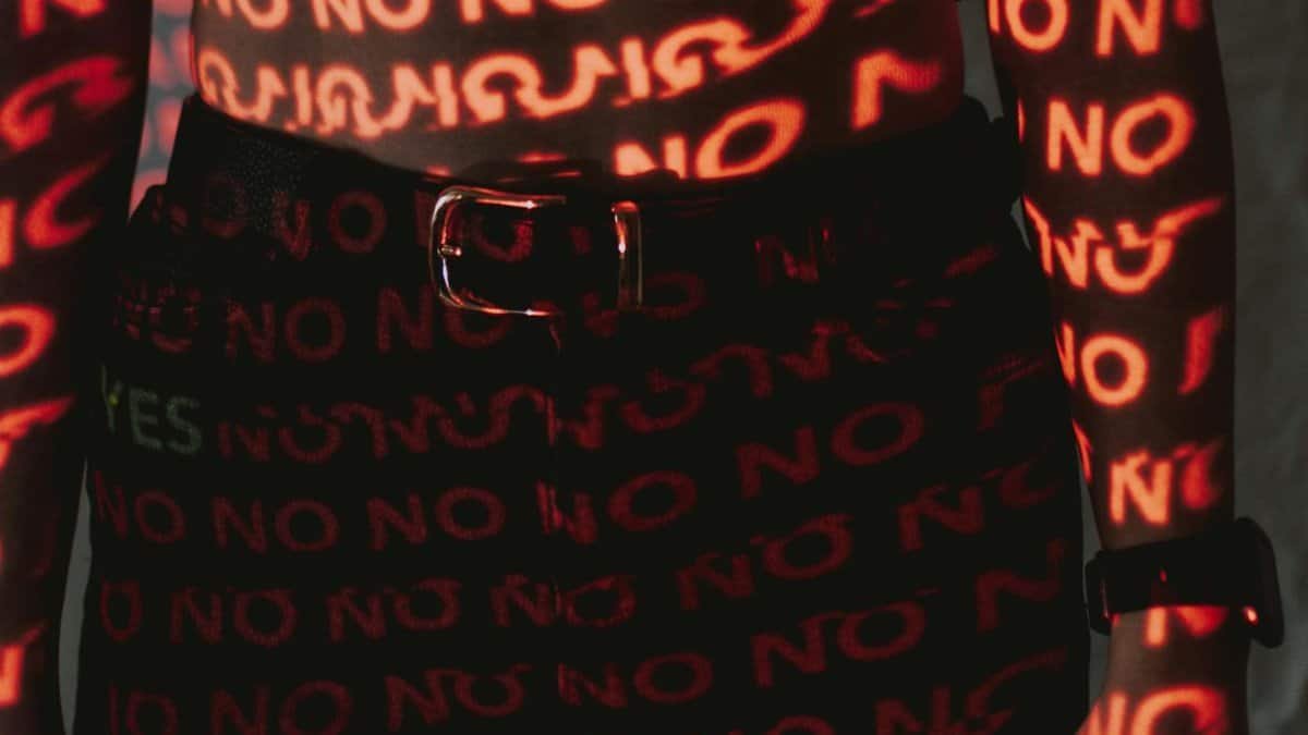 Illuminated words projected on a body creating a conceptual design with 'NO' text in red light.