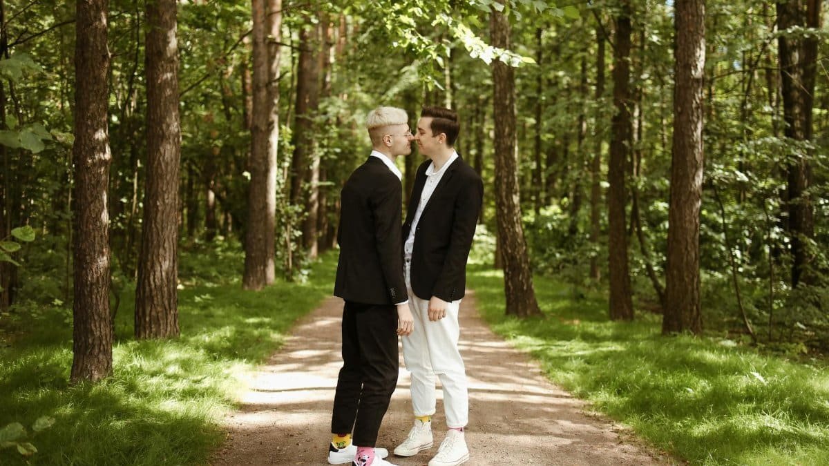 A loving couple sharing an intimate moment on a sunny forest path.
