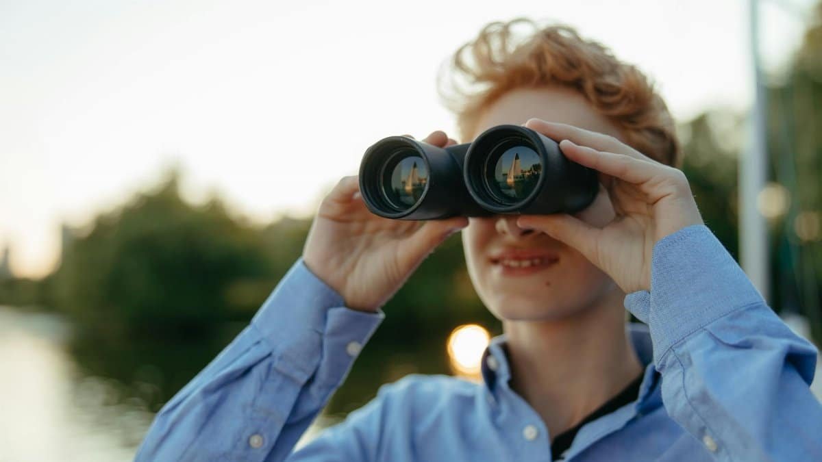 A young person uses binoculars during a nature observation adventure.
