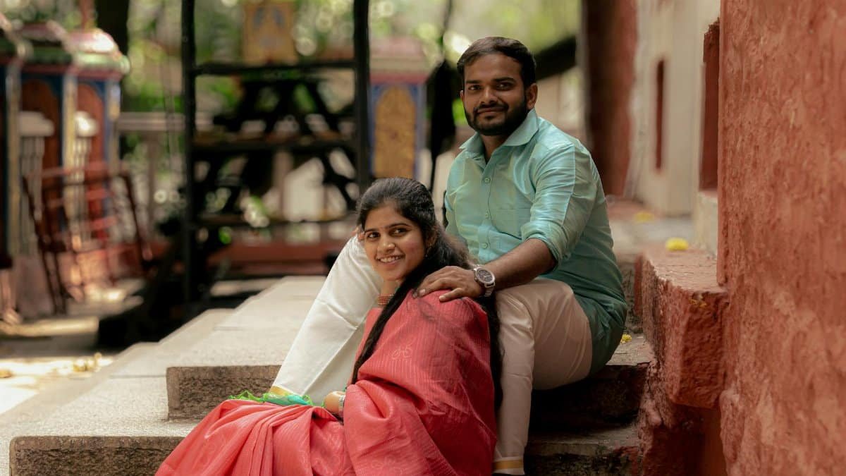 A cheerful couple sitting on outdoor steps in an urban area with historic architecture.