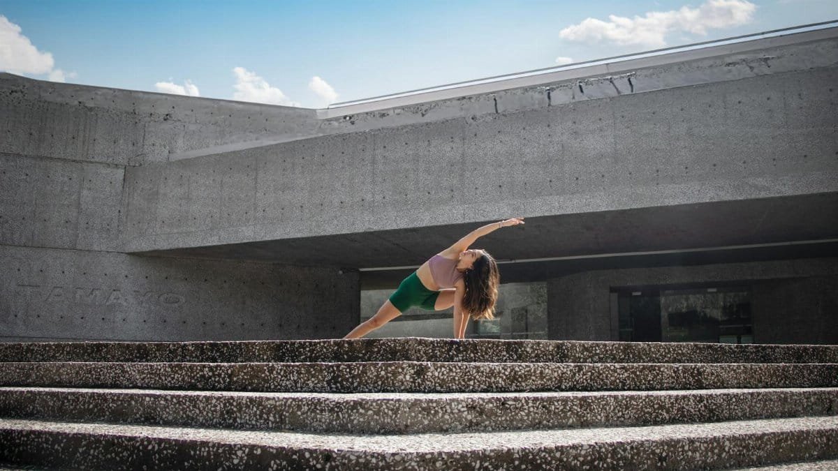 Woman performing yoga pose on stone steps in Ciudad de México, blending fitness and urban architecture.