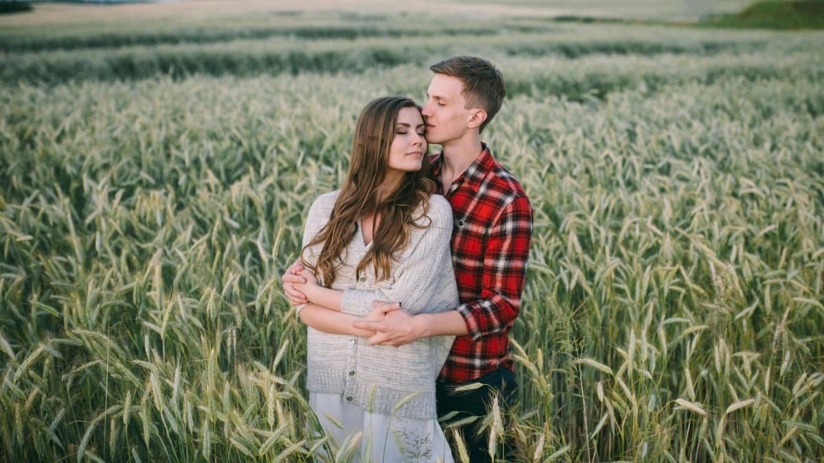 Couple sharing a tender moment while standing in a vast wheat field, conveying love and serenity.