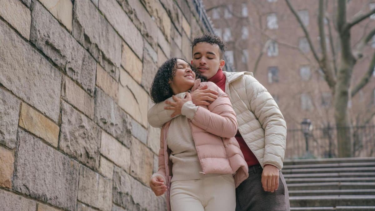 Happy couple embracing affectionately on urban steps in warm winter clothes.
