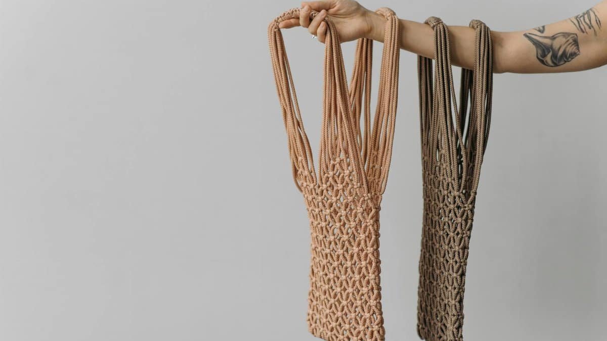 Close-up of an arm holding sustainable mesh bags showcasing tattoos.