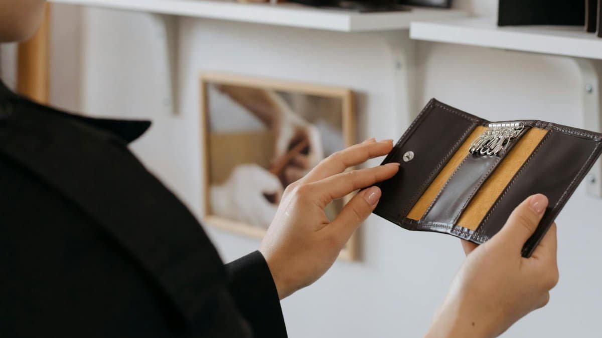 Close-up of hands holding a sleek leather keyholder indoors, showcasing design and craftsmanship.