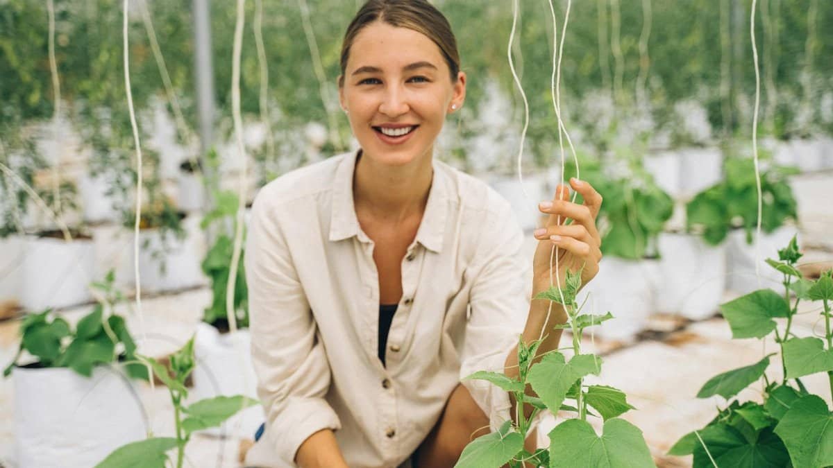 Smiling woman in a greenhouse showcasing modern indoor farming techniques.