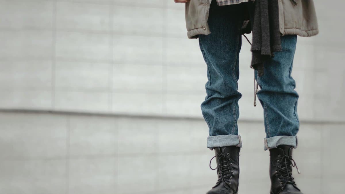 Trendy outfit featuring rolled denim jeans and black leather boots in a casual urban setting.