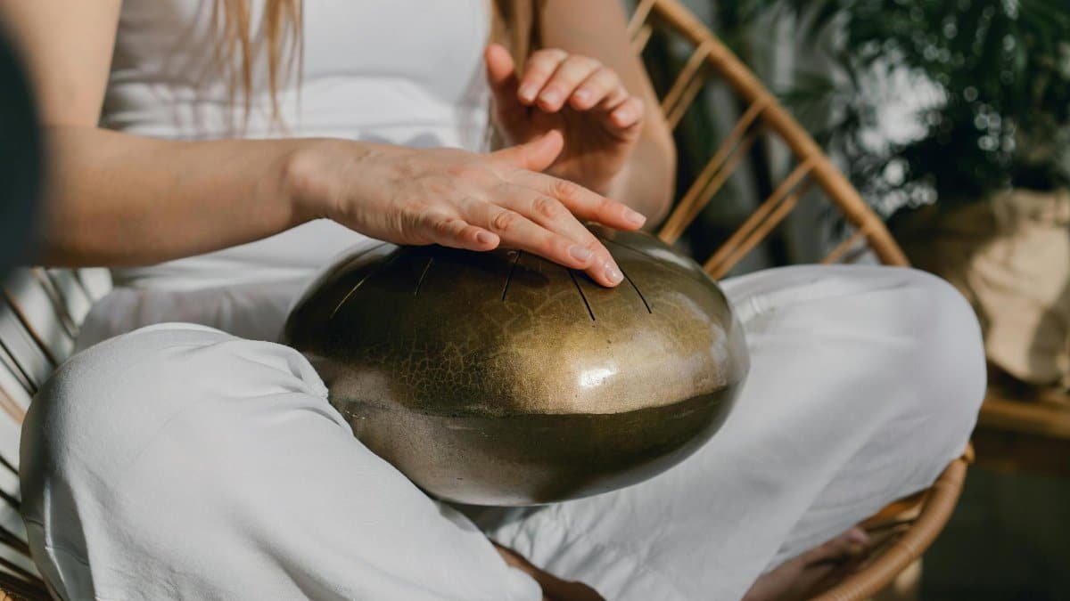 A person sits meditating, playing a handpan for relaxation and mindfulness.