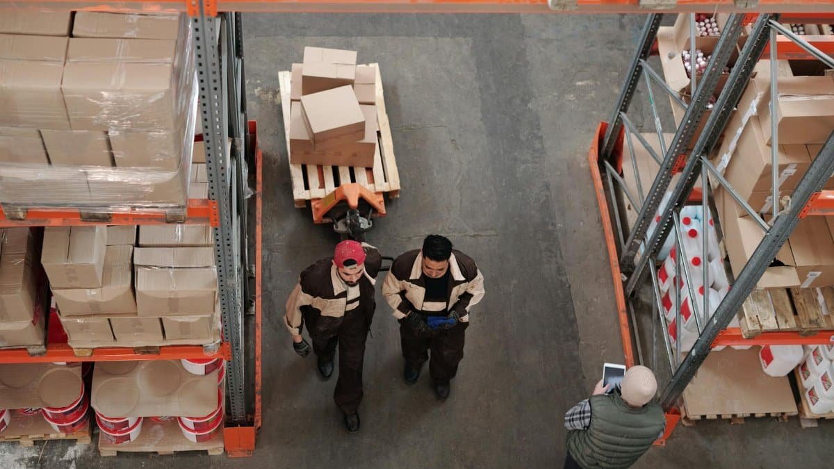 High angle view of warehouse workers organizing and preparing shipments with boxes and pallets.