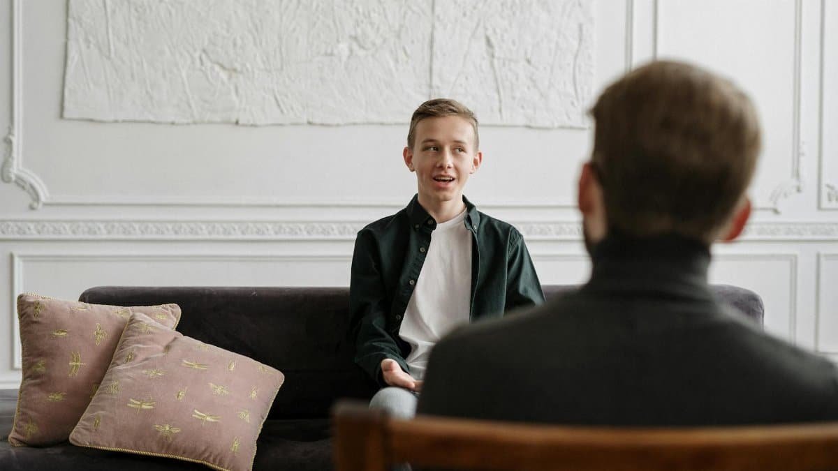 A young man engages in a therapy session with a counselor in a modern office setting.