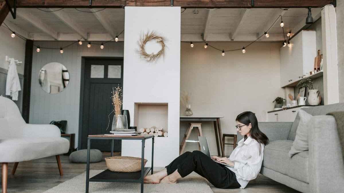 Cozy loft apartment with a woman working on a laptop, showcasing modern remote work lifestyle.
