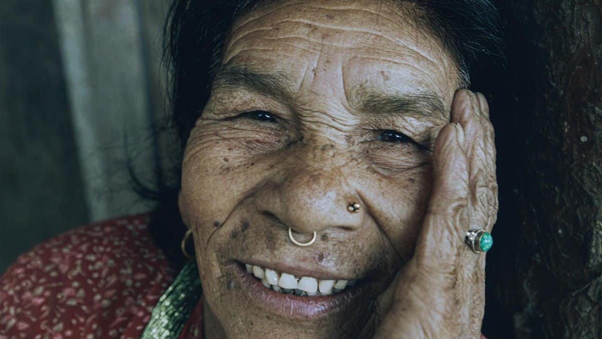 Close-up of a smiling elderly woman with a nose piercing showcasing her wrinkles and joyful expression.