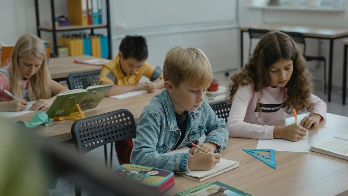 A group of children focused on studying in a classroom with books and stationery.