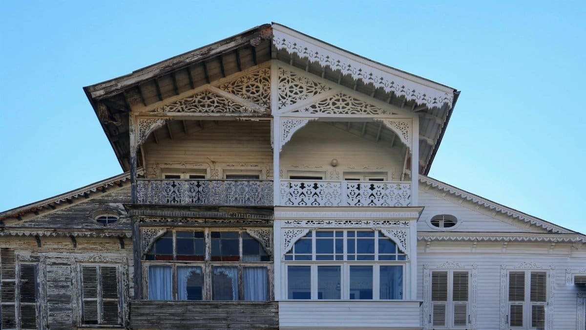 A detailed view of a half-renovated wooden house facade, showing old vs new.