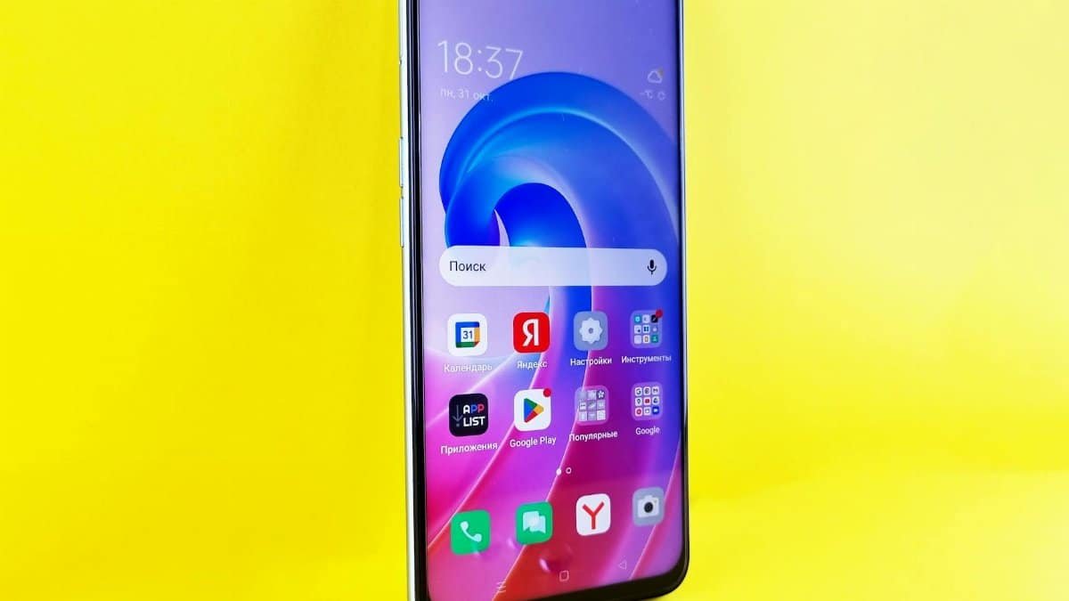 Close-up of a smartphone with colorful apps on a bright yellow surface.