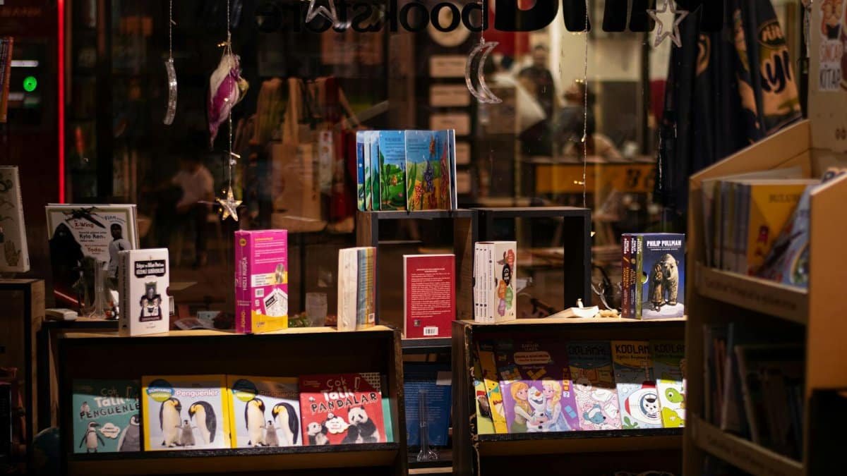 Warm and inviting bookstore window display showcasing colorful books at night.