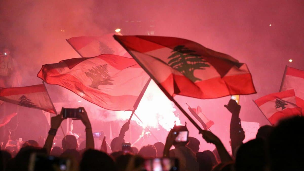 Vibrant night festival in Beirut with people waving Lebanese flags, capturing a moment of unity.