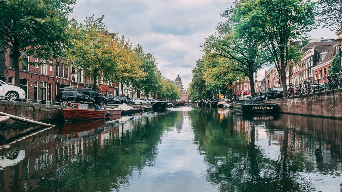 Scenic view of iconic Amsterdam canal with boats and historic buildings lining the waterway.