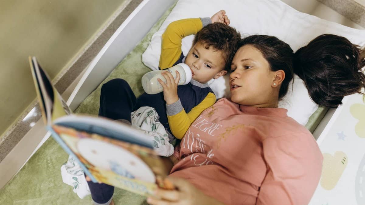A mother and her young son reading a book together in bed, fostering a bond through storytelling.