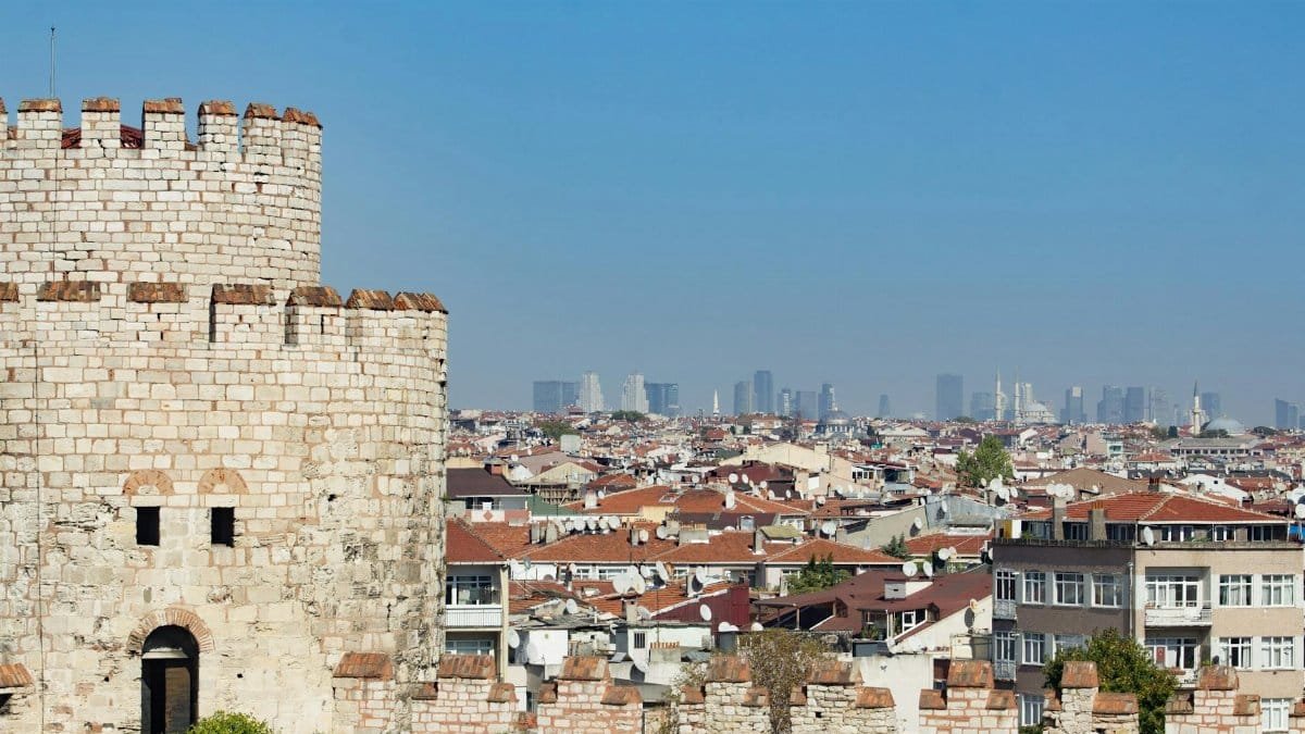 A historic stone tower overlooking the bustling skyline of Istanbul, showcasing a blend of ancient and modern architecture.