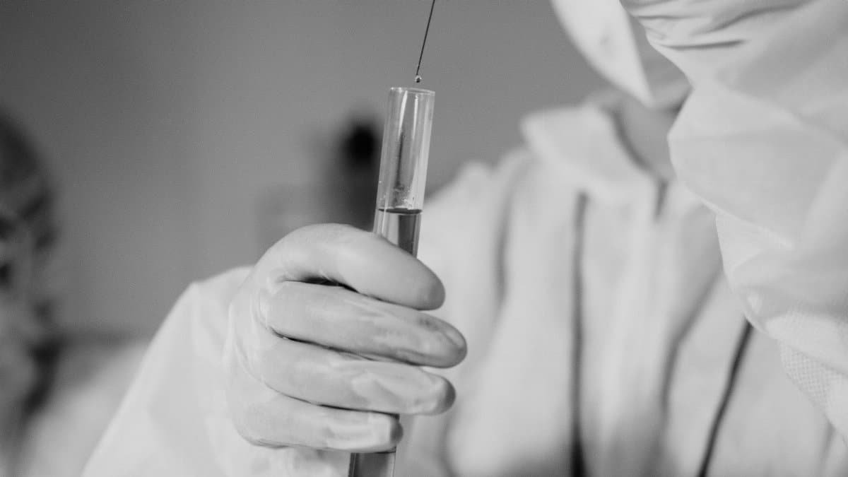 Scientist in protective gear working with test tube in laboratory.