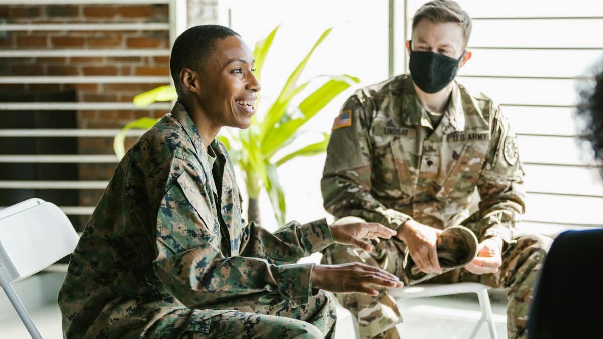 Soldiers in military uniforms discussing during a therapy session indoors.